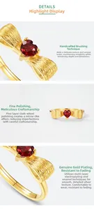 Macro detail of gold bow ring featuring manual brushed texture and red heart gemstone