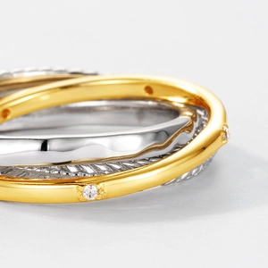 Macro shot of silver twisted cable ring and gold band set with sparkling zircon stones