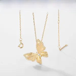 Close-up of golden butterfly pendant with brushed metal finish and white sparkling crystals