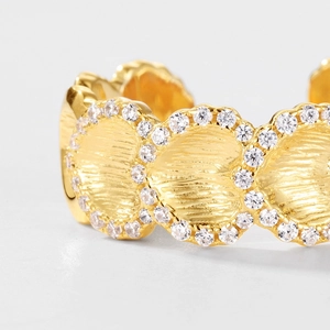 Macro shot of gold-plated ginkgo leaf ring with brushed texture and zircon crystals
