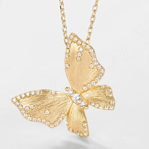 Macro shot of gold butterfly pendant featuring brushed metal texture and micro-inlaid stones