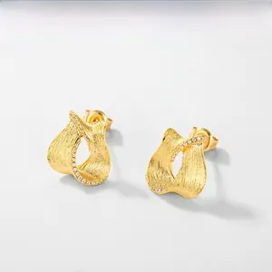 Close-up of golden brushed texture earrings with delicate micro-pave zircon detailing