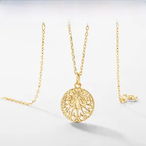 Close-up of a golden hollow leaf pendant necklace with intricate filigree on a fine chain