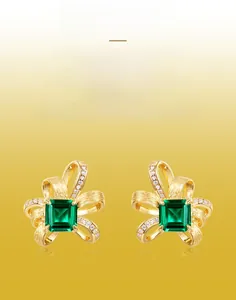 Macro detail of square emerald earrings with handmade brushed gold texture and small diamonds