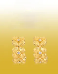 Detail of handmade brushed gold floral earrings with sparkling white stone centers