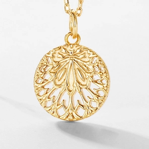 Macro view of gold hollow leaf pendant showing intricate mandala carving details