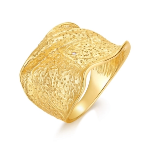 Golden wide band ring with irregular lava texture and a small sparkling center stone