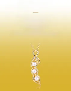 Détail macro du pendentif cosse de pois doré avec trois perles et fini en métal brossé