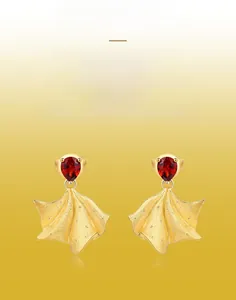 Gros plan sur des boucles d'oreilles dorées en éventail avec pierres rouges et fini brossé