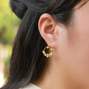 Elegant gold flower hoop earrings with zircon center on model in natural light