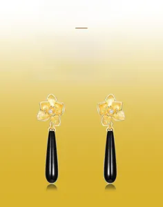 Macro detail of orchid earring featuring brushed gold texture and black onyx teardrop