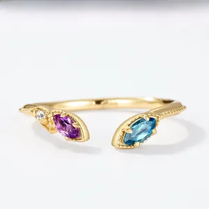 Detailed macro view of 10K gold open ring with marquise blue topaz and purple gemstone