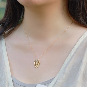 Elegant gold S925 silver necklace with monstera leaf pendant and a white pearl on model