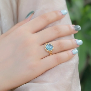 Bague en argent S925 plaqué or avec topaze bleue ronde et détails de motifs creux