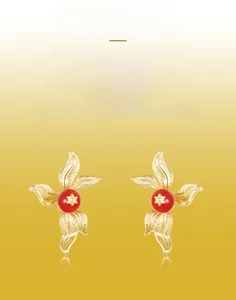Detail of vintage gold-plated leaf earrings with red agate and star embossing