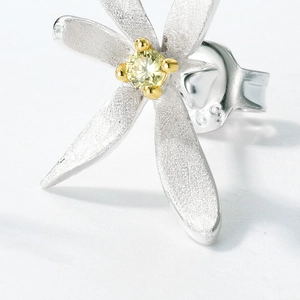 Macro detail of S925 silver flower stud earring with frosted petals and yellow zircon