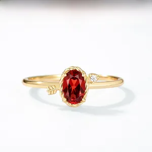 Macro de la bague flèche de Cupidon dorée avec un grand grenat rouge ovale et détails