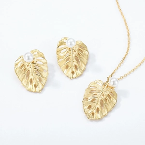 Golden monstera leaf jewelry set with brushed metal texture and white pearls