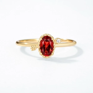 Détail macro de la bague en argent S925 dorée avec grenade rouge et flèche de Cupidon