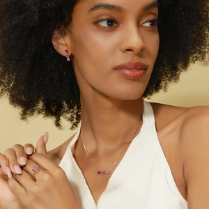 Detailed view of gold jewelry set with rectangular pink gemstones on a female model