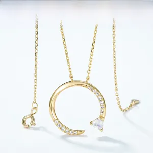 Dettaglio collana dorata con ciondolo ad anello a C e intarsio di pietra a cuore