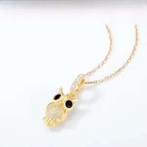 Gros plan du pendentif hibou doré avec zircons blancs et yeux en pierre précieuse noire