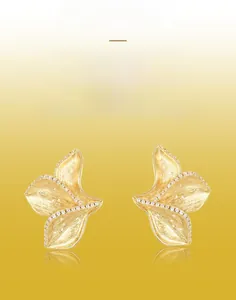 Macro detail of handmade brushed gold leaf earrings with sparkling zircon inlay