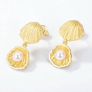 Élégantes boucles d'oreilles coquillages dorées avec perles blanches sur fond blanc