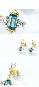 Détails rapprochés des boucles d'oreilles en argent S925 doré avec pierres bleues