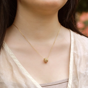 Close-up of golden quilted cylinder pendant with diamonds on a minimalist O-chain