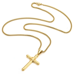 Detail of a golden twisted rope cross pendant with a classic box chain on white background