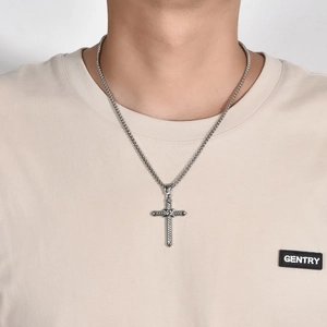 Macro shot of men's vintage silver cross pendant with twisted rope texture and bead chain