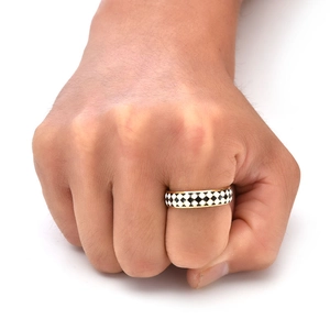 Detailed view of checkered black and white enamel pattern on a golden steel ring