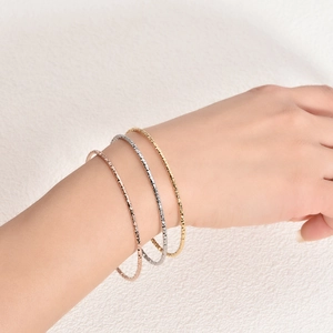 Detailed view of stacked 18K gold silver and rose gold thin bangles on wrist