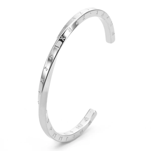 Macro detail of silver Mobius C-shaped cuff bracelet with engraved letters on steel surface