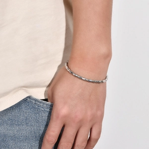 Vue détaillée d'un bracelet jonc torsadé argenté en forme de C sur un poignet masculin