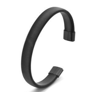 Macro view of black C-shaped cuff bracelet featuring a dense industrial spring texture