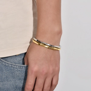 Detail of interlocking gold and silver titanium steel bangles with Roman numeral engravings