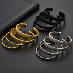 Set of three elastic C-shaped spring bracelets in black, gold, and silver finishes