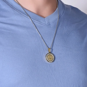 Détail du pendentif rond en acier titane doré avec calligraphie arabe et bordure en cristaux
