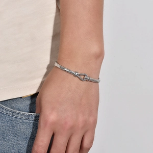 Nahaufnahme eines silbernen Mesh-Armbands mit markantem U-förmigem Hufeisenverschluss