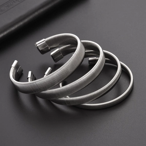 Detailed macro view of four stackable silver spring coiled C-shape metal bracelets