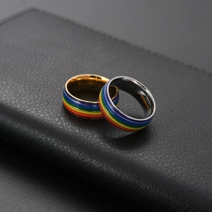 Macro de bagues en or et argent avec rayures émaillées arc-en-ciel sur cuir noir