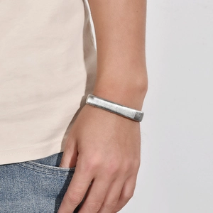 Close-up of silver elastic C-shaped cuff bracelet with vertical texture on model wrist