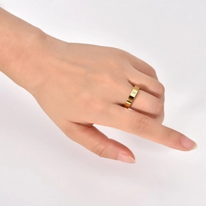 Detailed close-up of a 4mm minimalist gold band ring featuring a single zircon on finger
