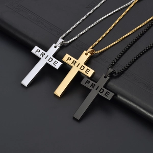 Trois pendentifs croix PRIDE en acier titane argent or et noir sur un carnet en cuir