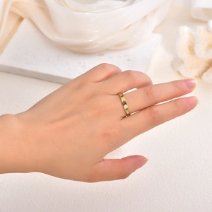 Close-up of a gold titanium ring featuring square blue and white gemstones on a hand