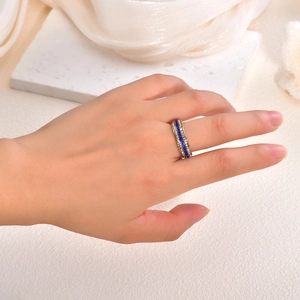 Detailed view of luxury gold ring with triple rows of blue and white crystals on a hand