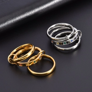 Macro detail of triple interlocking 18K gold and silver rings with multicolored crystals