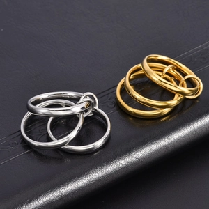 Macro shot of interlocking 18K gold and silver titanium steel triple rings on black leather
